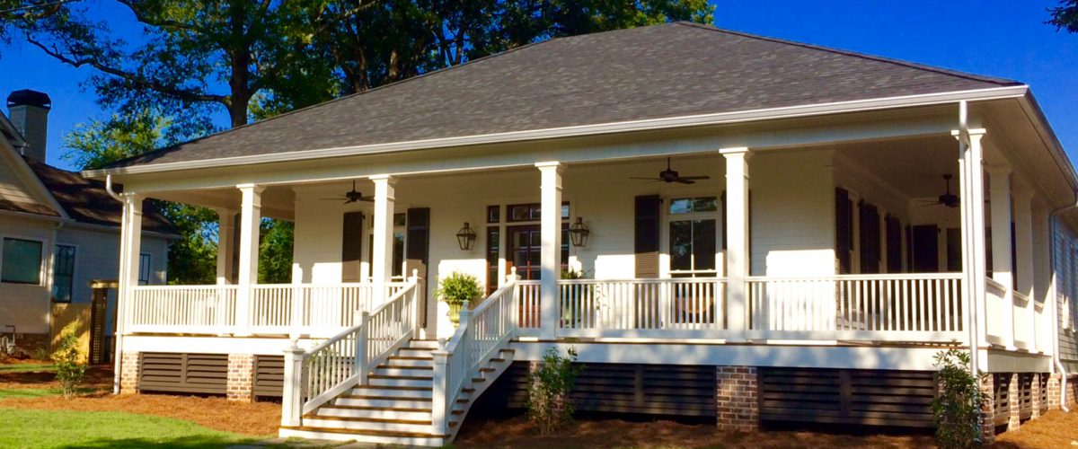 White custom home with a columned wraparound porch and front steps