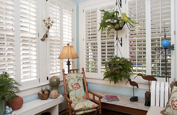Sunroom with plantation shutters, wicker furniture and a light-blue ceiling