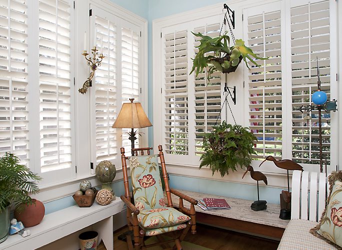 Sunroom with plantation shutters, wicker furniture and a light-blue ceiling