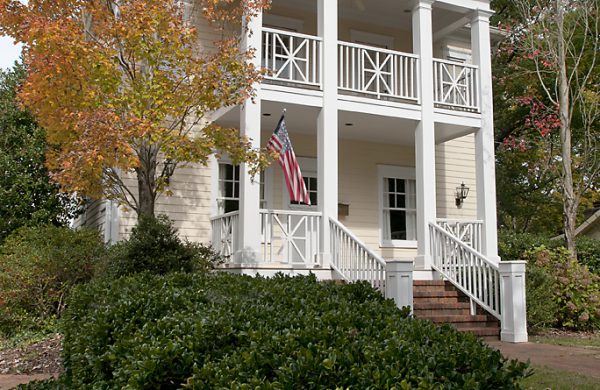 Two-story white custom home with a columned porch amid autumn foliage