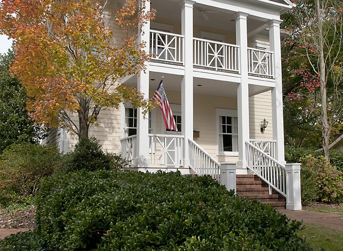 Two-story white custom home with a columned porch amid autumn foliage