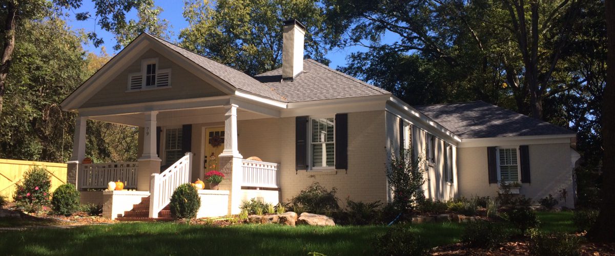 Cream custom home with a columned porch and dormers on a wooded lot