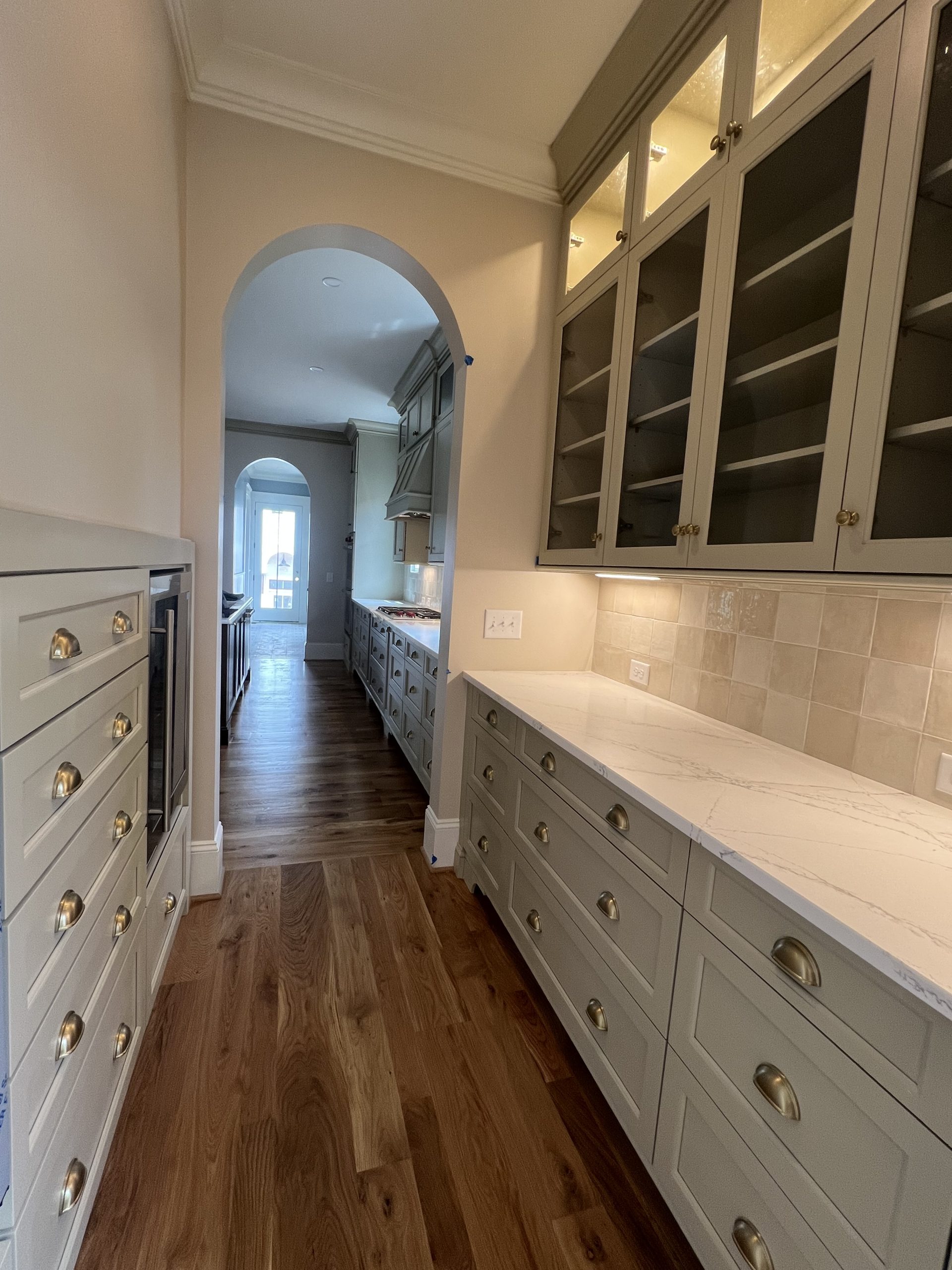 Butler's pantry with glass-front cabinets, marble countertop and hardwood floors